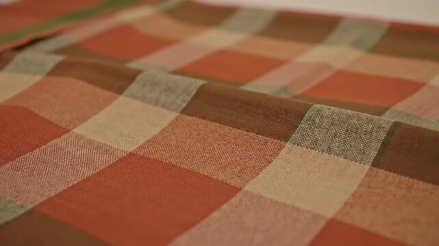 Close-up of a checkered textile with warm earth tones, folds, and subtle texture