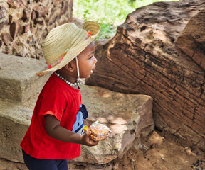 village african girl child, straw hat and red shirt, outdoors in the nature , sand ground