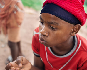 single african child in the village, outdoors in the nature , wearing a red beanie