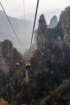 View of cable cars traverse the misty, towering peaks of Zhangjiajie, a symphony of nature's grandeur and human ingenuity, Zhangjiajie, Hunan, China.
