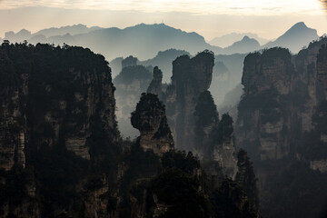 View of towering sandstone pillars shrouded in mist, jutting from the earth in a surreal landscape, Zhangjiajie National Forest Park, Zhangjiajie, Hunan, China.