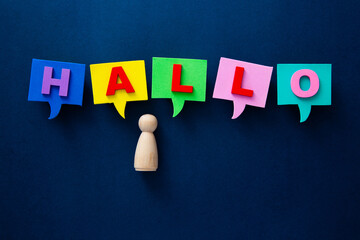 Wooden figure welcoming with colorful hallo speech bubbles