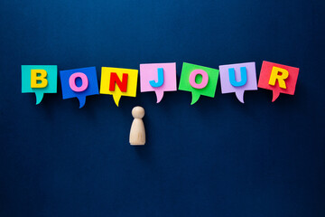 Wooden figurine learning french greeting bonjour in speech bubbles