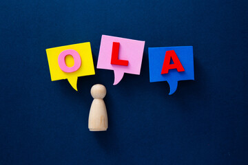Wooden figurine speaking hola in colorful speech bubbles