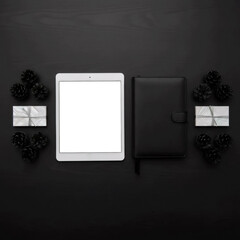 tablet with white screen and black diary on dark background with decor