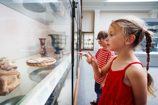 Two kids on excursion observe ancient artifact in glass case