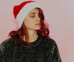 Portrait of a serious tired dreamy with eyes closed young woman in a Santa hat , retro style photo