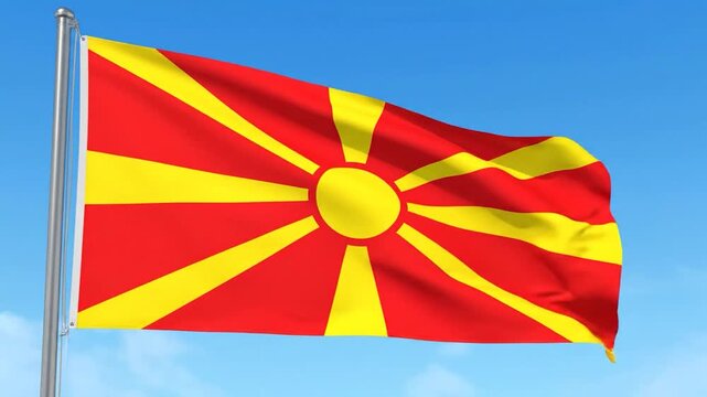 The bright red and yellow flag of a country flies against a blue sky