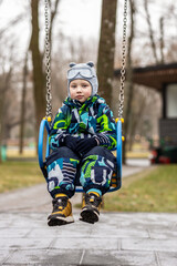 Five-year-old boy riding a swing in a winter park