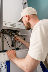 Repairman checks gas boiler for maintenance in residential bathroom