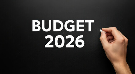 Hand writing the word budget 2026 on a black chalkboard, emphasizing financial planning and management concepts for the upcoming year