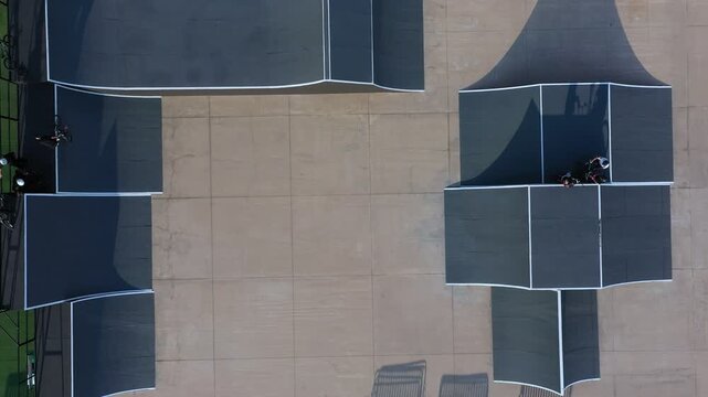 Biker performing tricks in a urban skatepark with ramps and shadows