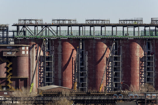 View of massive, cylindrical structures rise against the sky, their weathered red surfaces contrasting with the intricate steel framework above, Beijing, Beijing, China.