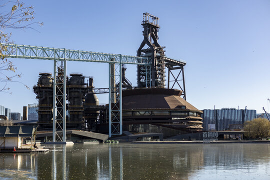 View of the formidable steel plant, a relic of industry mirrored in the still waters, against a clear sky, standing as a monument, Beijin, Beijin, China.