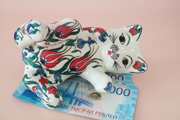 Ceramic toy cat and paper bills. Russian rubles.