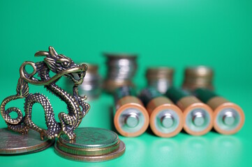 A dragon figurine on a background of batteries and coins.