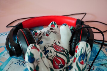 Ceramic cat figurine, headphones and paper bills. Russian rubles.