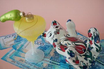 A ceramic cat figurine, a toy cocktail glass, and paper bills. Russian rubles.