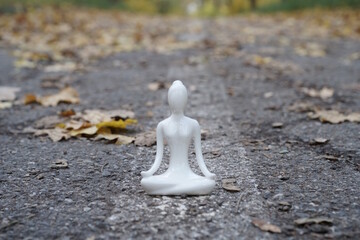 Porcelain figurine of a meditating woman against the background of autumn leaves.