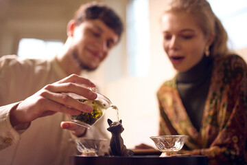 Close-up of tea infusion poured between cups during ceremony. Concept of premium tea presentation, visuals for advertising, packaging design inspiration and beverage marketing materials.