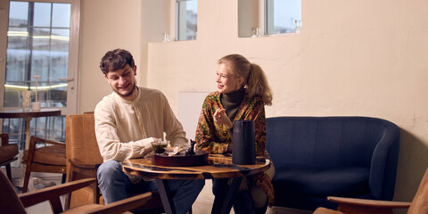 Couple observing tea infusion during relaxed indoor tea ceremony. Concept of tea drinking rituals for hospitality branding, cafe promotion, wellness advertising, and mindful consumption campaigns.