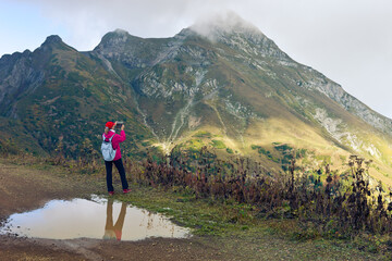 Woman takes pictures of mountain landscape with mobile phone