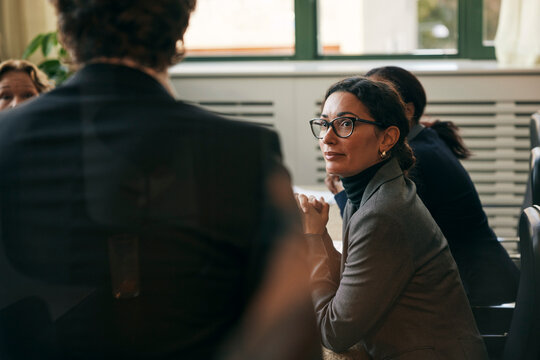 High angle view of female lawyer sitting in meeting with colleagues at board room