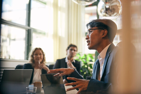 Male lawyer discussing business strategies with colleagues in meeting at board room