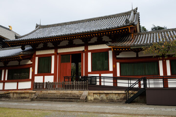 Fototapeta premium Traditional East Asian Temple Building With Red Columns, Green Shutters, And Tiled Grey Roof. Nara City, Japan