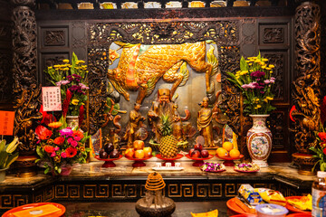 Taipei City, Taiwan - 12 April 2025: View of the vibrant altar at Songshan Ciyou Temple, adorned with golden carvings, fresh flowers, and offerings of fruit, illuminated by soft light.
