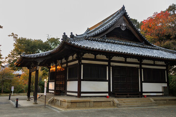 Fototapeta premium Ancient Japanese Temple Gate With Large Bell And Curved Roof In Serene Garden Setting. Nara City, Japan