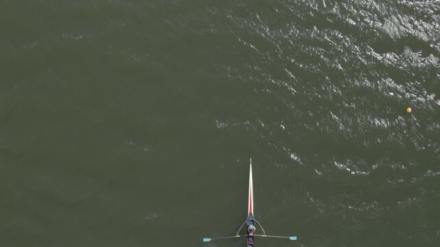 Aerial view of a rower glides across the water, the boat cutting a path through the dark green water, Ciudad de la Costa, Departamento de Canelones, Uruguay.