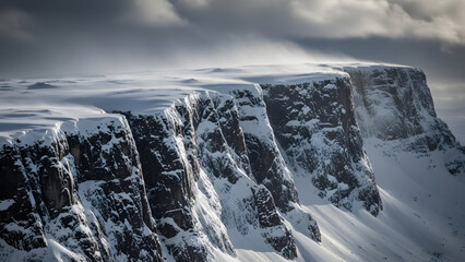 Dramatic snow-covered cliffs rising majestically under a cloudy sky showcasing rugged winter landscape and vastness of nature in cold, powerful, and breathtaking outdoor scenery