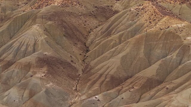 Aerial view of the rugged terrain with contrasting hues of brown and beige creating a textured landscape, Calanchi del Cannizzola, Sicilia, Italy.