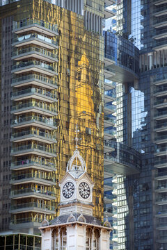 Singapore, Singapore - 14 May 2024: View of the elegant clock tower juxtaposed against the modern, reflective skyscrapers, creating a striking contrast of old and new.
