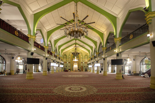 Singapore, Singapore - 13 May 2024: View of the grand interior of Masjid Sultan, where ornate chandeliers hang above a sprawling carpet, bathed in a warm, inviting light.