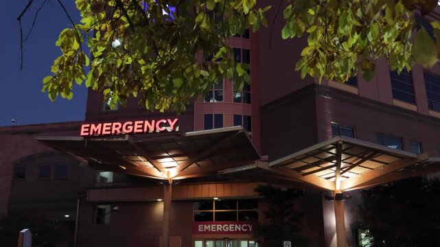 Hospital Emergency Room Entrance with Red Signage. Emergency Sign at Hospital in USA. Emergency Room and Medical Care Building. Hospital, Medical Center, Emergency Room. Evening Night Times.