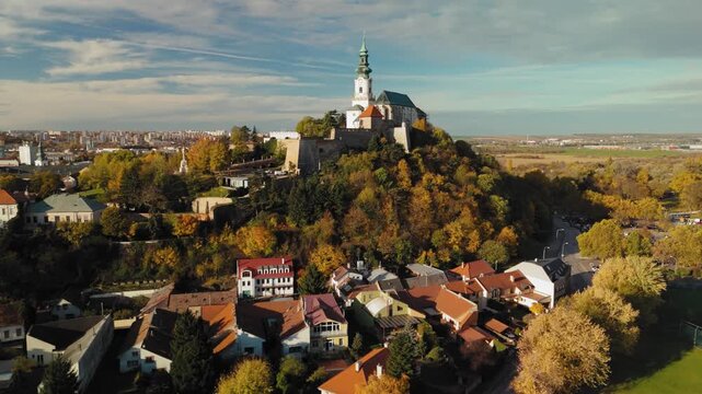 Aerial view of Nitra Castle perched atop a hill, surrounded by vibrant autumn foliage and quaint buildings, Nitra, Nitra Region, Slovakia.