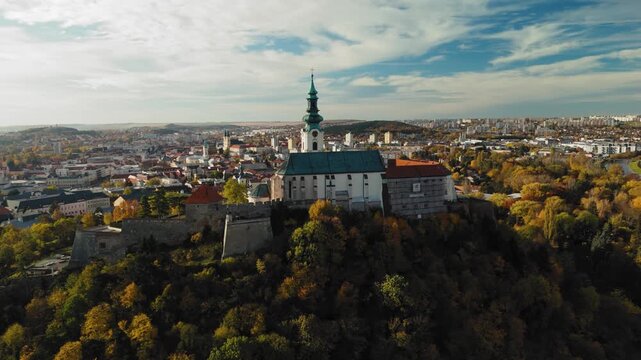 Aerial view of Nitra Castle atop a hill, with autumn foliage adding a warm contrast to the city skyline, Nitra, Nitra Region, Slovakia.
