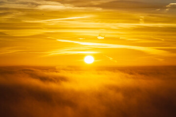 Aerial view of a radiant sun piercing through a sea of clouds, painting the sky in hues of gold and amber, Henley-on-Thames, Oxfordshire, England.