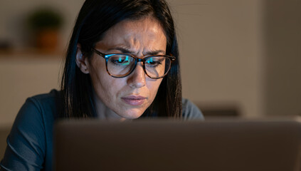 Woman concentrating on laptop screen struggling with work or studies