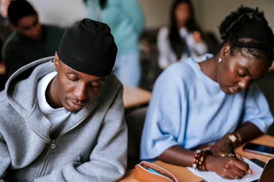 Focused young male student wearing do rag studying in university at classroom