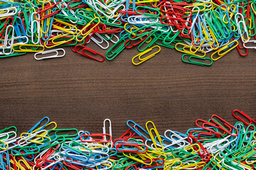 Top down photo of multicolored paper clips on the wooden table with copy space.