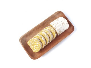 Fresh tempeh slices on wooden plate isolated on white background. Flat lay 