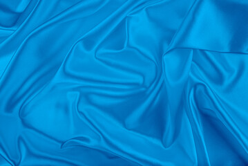 Obraz premium Elegant blue satin fabric draped in a soft circular swirl pattern with glossy highlights.