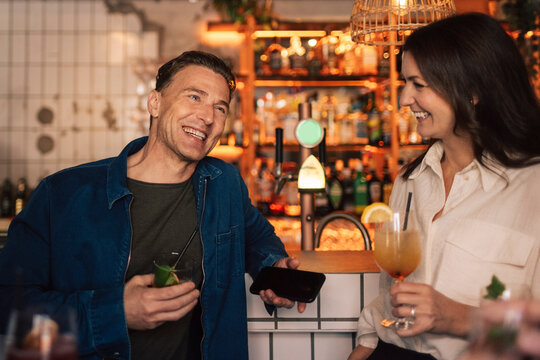 Smiling male and female friends enjoying together at bar party
