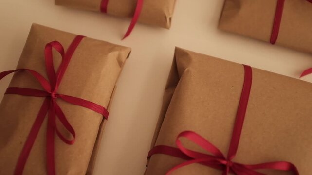 Christmas presents wrapped in brown craft paper and tied with thin red ribbon. Simple and modern wrapping aesthetics. Winter holidays gift giving tradition. Secret Santa.
