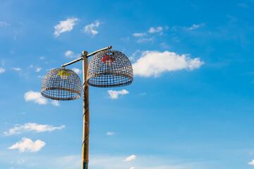 Lamps made from chicken coop with blue sky. Handmade bamboo lighting. Lamp holder from woven bamboo basket. Traditional handmade bamboo chicken coops repurposed as creative outdoor hanging lamps.