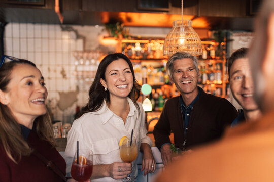 Group of cheerful friends spending leisure time together in cocktail party at bar