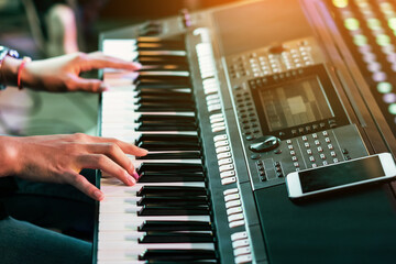 Hands of male musician press digital electronic keyboard synthesizers on concert stage. Pianist man hands play the keys of electronic piano. Piano music pianist hand playing. Selective focus on hand.